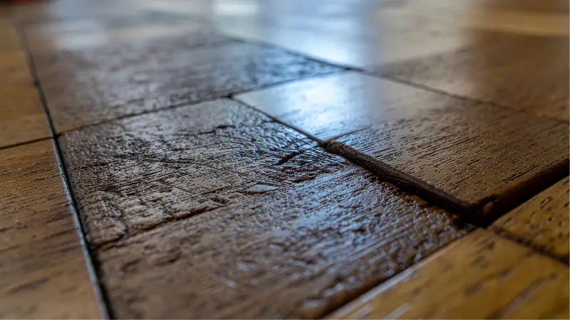 Close-up of a wood floor with a raised seam from water damage